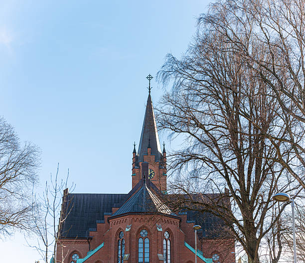 Red brick church with tall spire under clear blue sky
