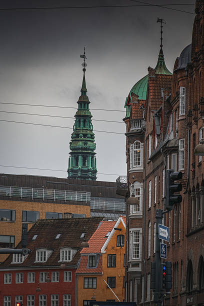 Historic Danish architecture with ornate balconies, storefronts, and pedestrians under moody urban sky