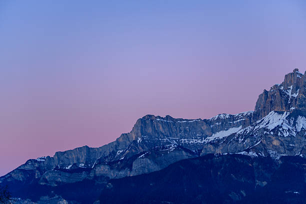 Snow-dusted limestone ridges of Aup de Veran stand against a soft gradient of pink and blue morning sky, creating a tranquil alpine winter scene.