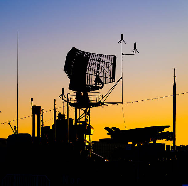 Military radar installation silhouetted against dramatic sunset sky