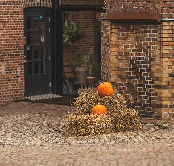 Autumn pumpkins on straw bales near rustic brick building