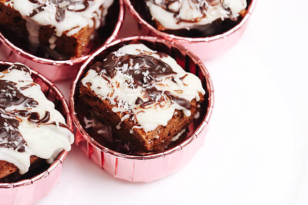 Individual dessert portions for bakery display and catering. Closeup of glazed chocolate cake squares.