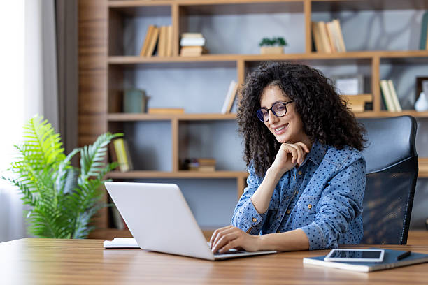 istock Smiling woman working on laptop in home office environment 2255563056