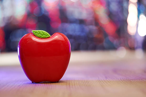 red plastic apple shape pencil holder on wood table top