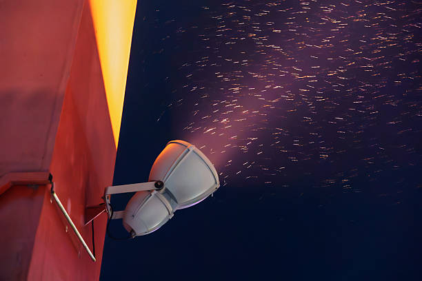 istock Close-up of a spotlight on a red wall illuminating falling snow at night 2255574112