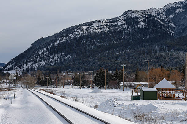 View down train track in winter, mountains and forest distant, Crowsnest Pass, Canadian Rockies
