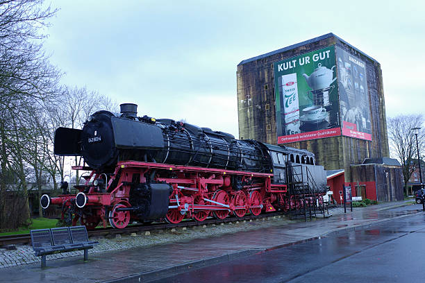 Emden, Germany - Jan 1 2026 Memorial steam Locomotive stands in front of a High bunker from WWII near the station. This freight locomotive was built in 1943 by the Compagnie Genérale de Construction de Locomotives Batignolles-Chatillon in Nantes-St. Joseph, France, under factory number 695.