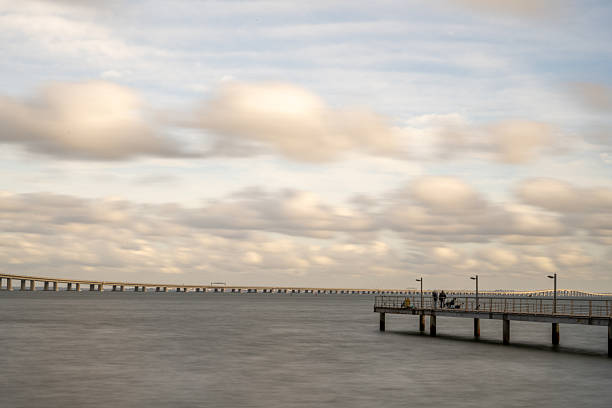 Lisbon Portugal December 18 2025. Vasco da Gama Bridge is seen from the riverbank with a pier extending into the Tagus River.