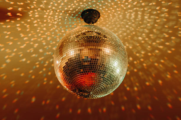istock disco ball with mirror surface and bright rays, orange color, hanging on ceiling, night party background 2255582023