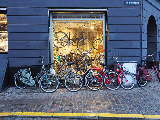 Colorful bicycles parked outside a bike shop with display window on cobblestone street, Copenhagen, Denmark