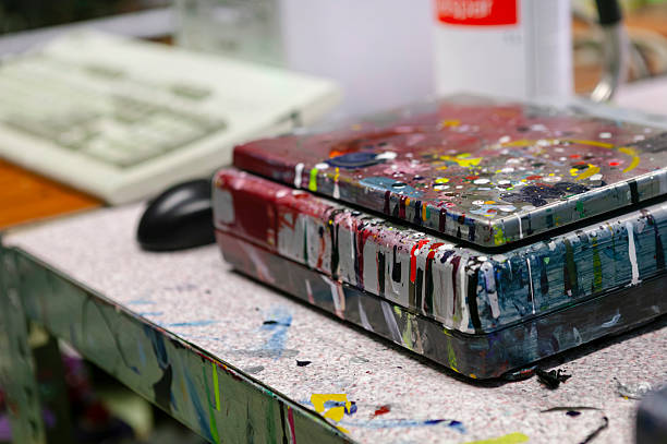 Colorful paint-splattered plastic mixing trays on studio table. Artist workspace, creative process, and painting supplies for art education and studio documentation.