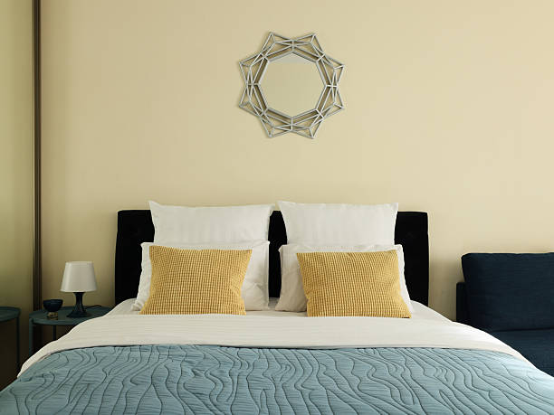 Modern clean bedroom reflected in geometric mirror. Freshly made bed and bright fresh room.