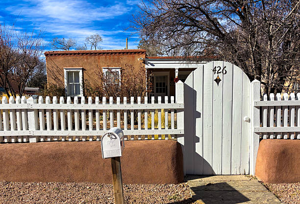 Santa Fe, NM - January 5, 2026: An old adobe house in downtown Santa Fe surrounded with a charming white picket fence and gate.