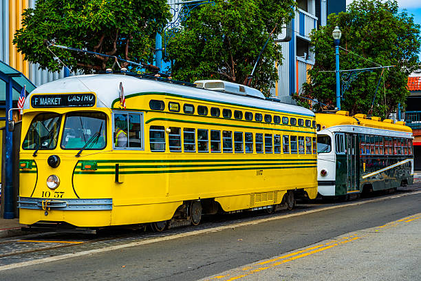 A Coral Gables Trolley stops along Ponce de Leon Boulevard in Coral Gables, Miami, Florida. The classic red and green city trolley, with a bicycle mounted on the front rack, is framed by tropical palm trees and bright South Florida skies. The image highlights the charm and functionality of Coral Gables’ local transportation system.