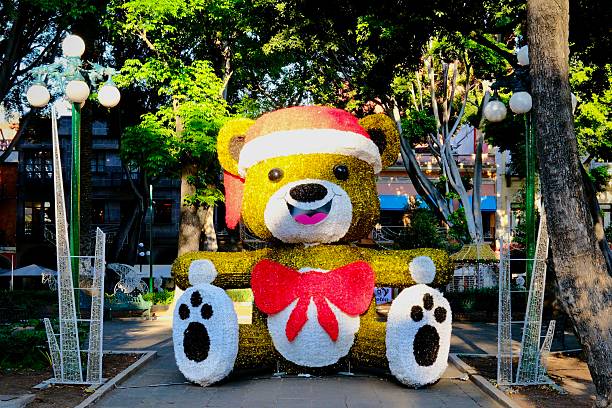 Puebla, Puebla, Mexico – December 28, 2025: A large illuminated teddy bear wearing a Santa hat stands as a seasonal installation in a public plaza in Puebla’s historic center.