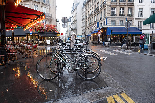 Early morning Paris street on a rainy winter day with parked bicycles, closed cafés, and a wet road. Calm urban atmosphere, travel, city life, and seasonal mood.