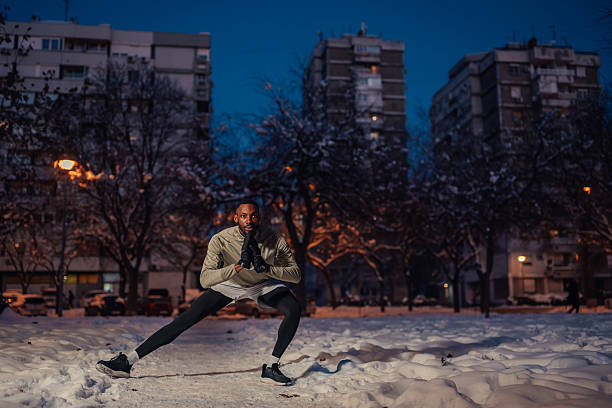 Determined man stretching outdoors in snowy park at night
