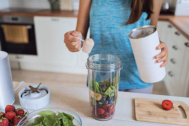 A young woman cuts strawberries and prepares a fresh smoothie, promoting clean eating and wellness.