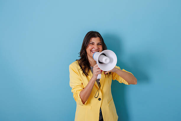 istock Young woman confidently shouting through megaphone, making a loud announcement with copy space 2255604138