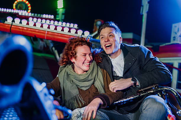 istock Young couple laughing enjoying carnival ride at night 2255605970