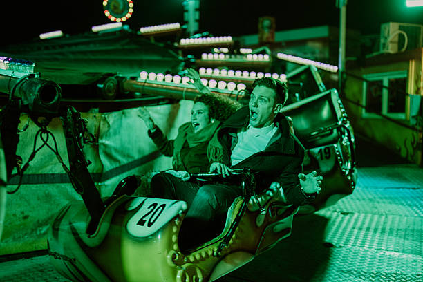 istock Couple screaming while enjoying thrilling amusement park ride at night 2255606024