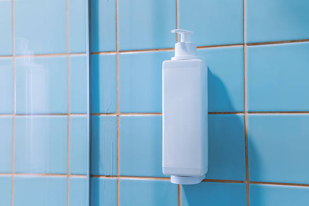 Wall mounted dispenser bottle on blue bathroom tiles in a clean minimal shower interior
