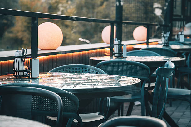 Restaurant patio with tables and chairs in an outdoor setting, illuminated by ambient lighting, waiting for customers