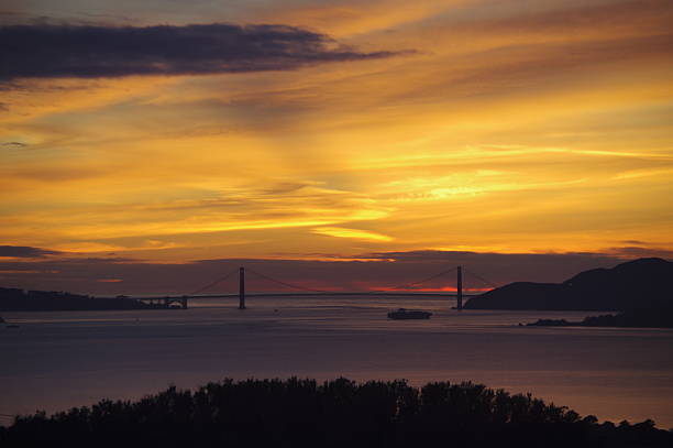 Golden Gate Bridge with Cargo Ship Passing Underneath at Sunset
