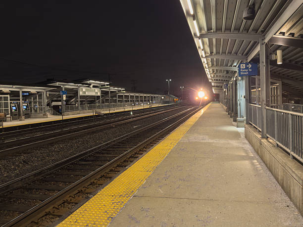 Train headlights approaching  Lombard Chicago Metra train station platform at night.