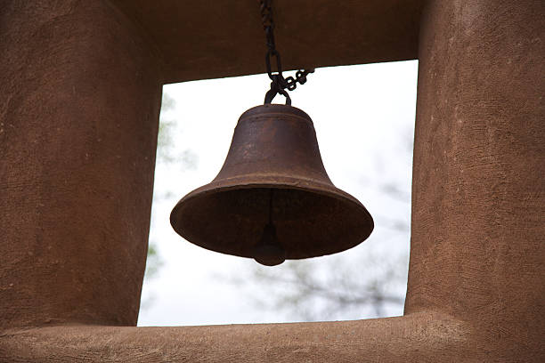 Rusted bell, adobe wall