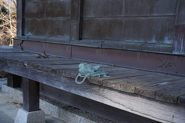 A wooden bench with a green bag on it. The bag is laying on the bench and the bench is outside