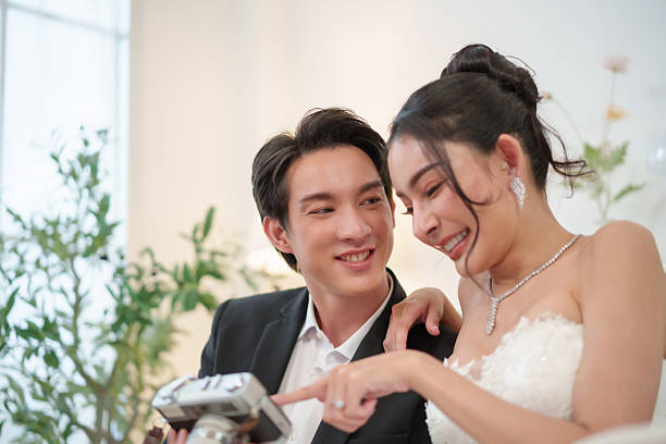 istock Asian newlywed couple smiling while viewing camera photos 2255624919