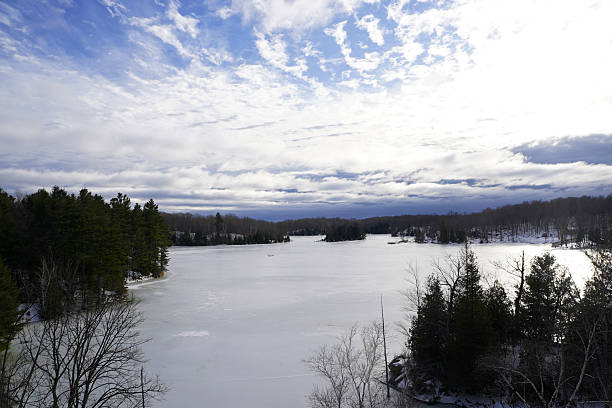 Beauport lake and snowy mountain during a winter day with boat garage, shacks, and pier