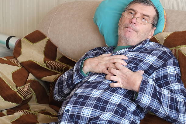 Senior man feeling chest pain while lying on sofa, heart attack symptoms.1