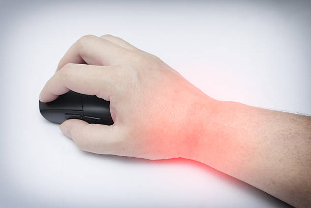 A close-up shot of a human hand operating a black wireless computer mouse on a clean white surface, with red spot on the wrist, highlighting office ergonomics and digital workflow