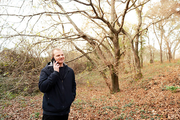 Smiling man standing in forest making a phone call outdoors