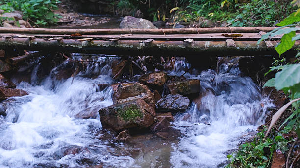 Water stream flowing down under wooden bridge in the forest