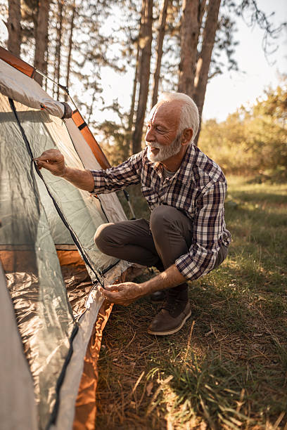 istock Senior man setting up camping tent in forest 2255642559