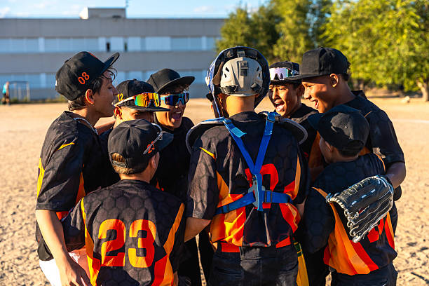 Young male baseball players huddling on the field, smiling and celebrating together after a game, showing teamwork, camaraderie and youthful excitement in summer outdoors
