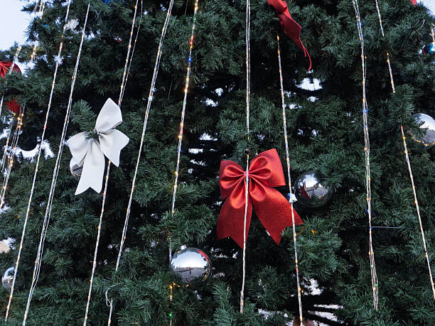 istock Decorated Christmas tree with red and white bows and silver baubles. Festive holiday background with vertical string lights. Winter celebration texture 2255646939
