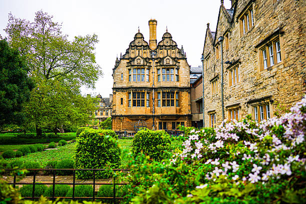 A peaceful view of Trinity College gardens at the University of Oxford, featuring the historic 17th-century Garden Building and a bronze armillary sphere surrounded by spring flowers. The classic golden stone architecture and manicured lawns capture the serene academic atmosphere of Oxford.