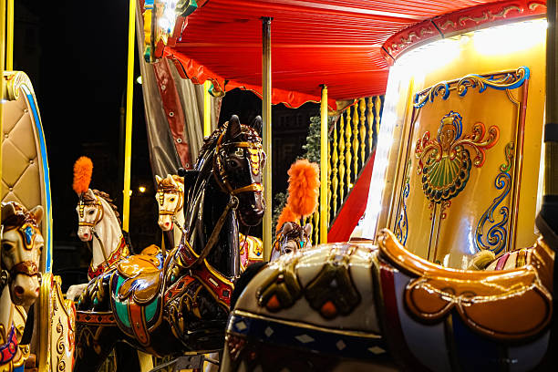 Beautiful old shiny carousel with toy pony horses in the historical town in Europe. Beautiful magic night cityscape