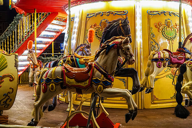 Beautiful old shiny carousel with toy pony horses in the historical town in Europe. Beautiful magic night cityscape