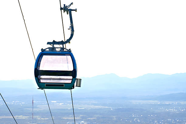 Blue cable car gondola high above mountain landscape. Aerial transportation system for ski resort or scenic travel. Modern technology for tourism.