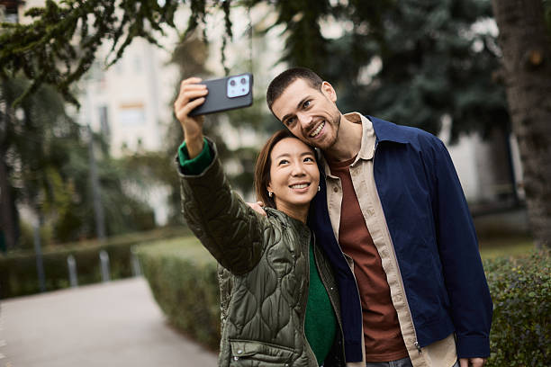istock A young mixed race couple is taking a selfie while walking down a city street. 2255661106