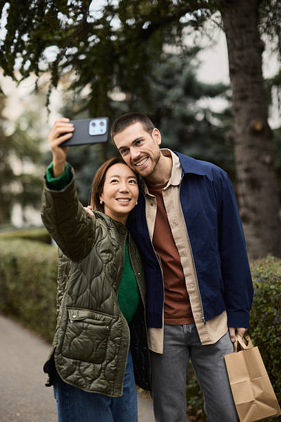 istock A young mixed race couple is taking a selfie while walking down a city street. 2255661298