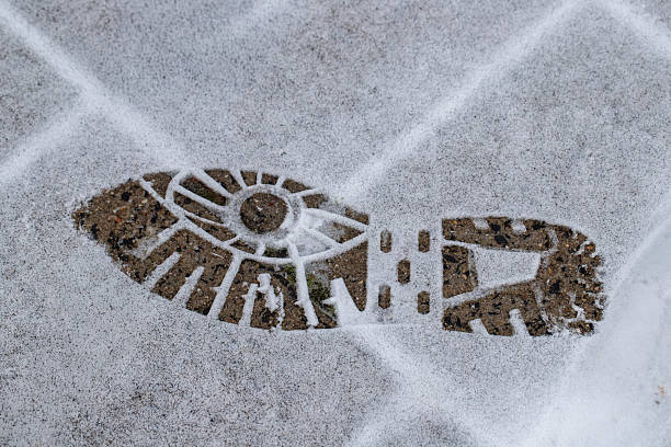 A footprint in the snow on a sidewalk.