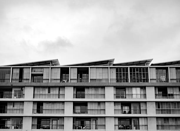 The side of a contemporary city building with windows and details, photographed in black and white to accentuate architectural textures.