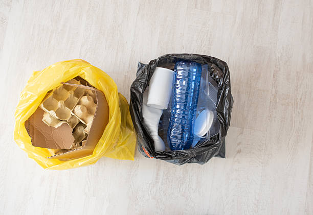 Sorting paper and plastic waste in bags on light floor with place for text, ecology blog, recycling service.