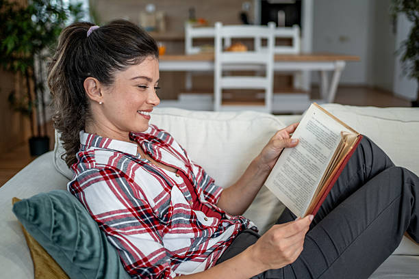 istock Woman relaxing at home reading book on sofa 2255675620